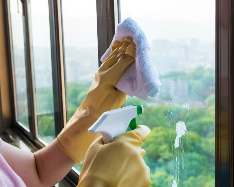 Foto de pessoa limpando vidro com receita de vinagre.