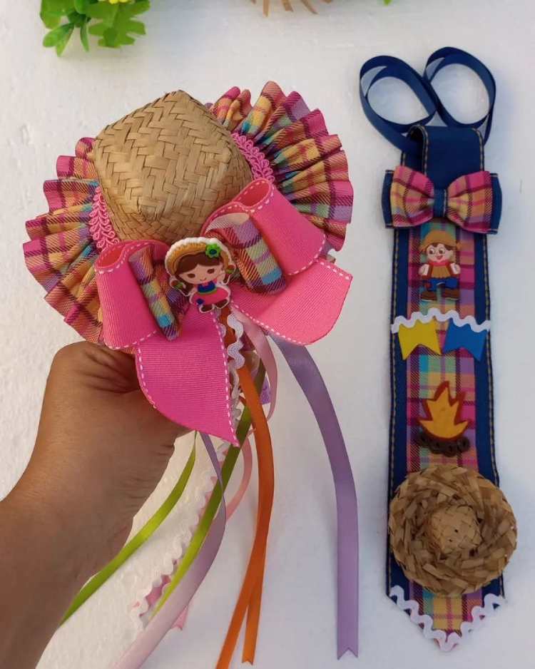 chapéu de palha pequeno com decoração de tecido floral e fitas coloridas. Ao lado gravata decorada nos mesmos tons, rosa e azul