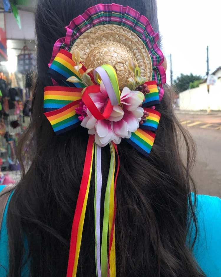 presilha em cabelo escuro decorada com chapéu de palha, flor e fitas coloridas