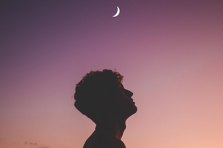 homem sem camisa olhando para o lado em um céu com lua minguante 