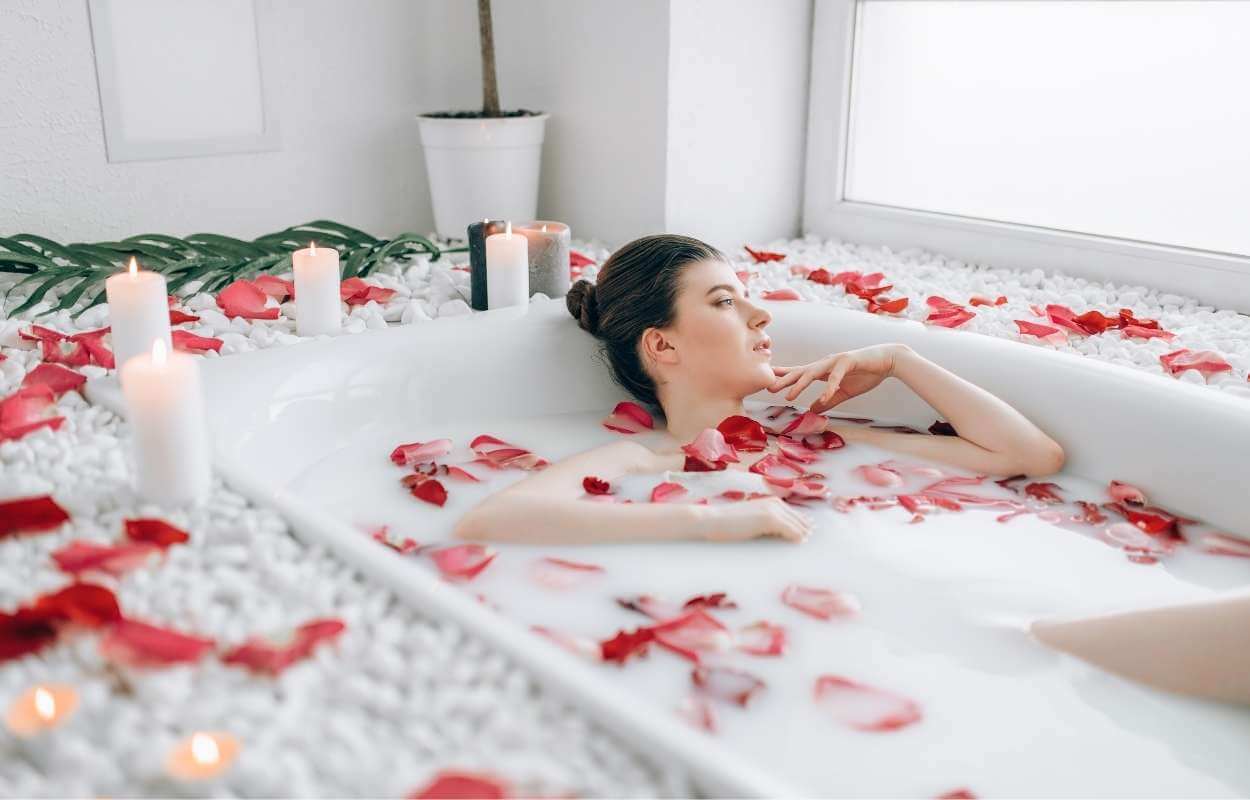 Mulher tomando banho de rosas vermelhas