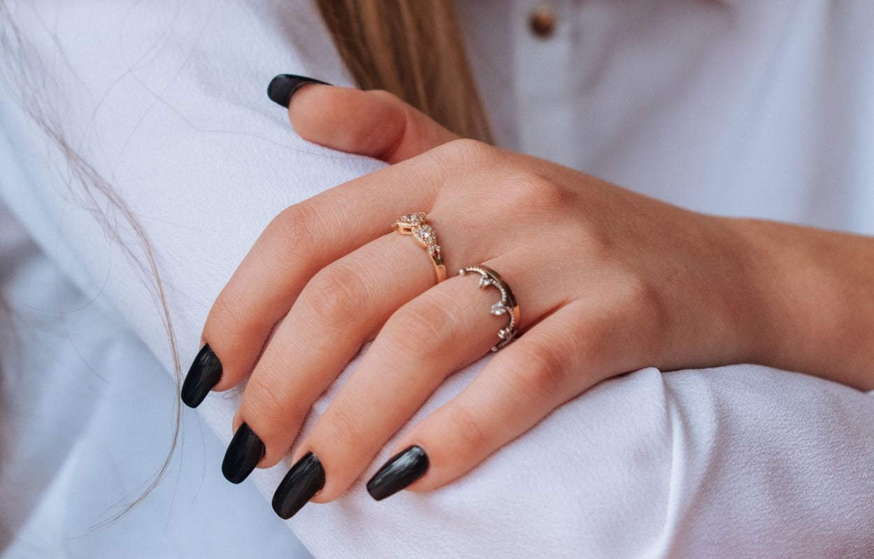 Mão de mulher com dois anéis, esmalte preto e dedos mais finos no inverno