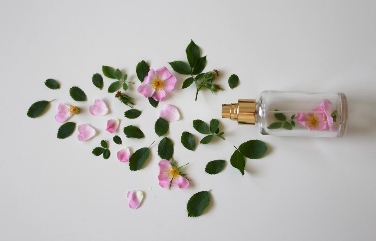 frasco de perfume com flores rosas e folhas verdes