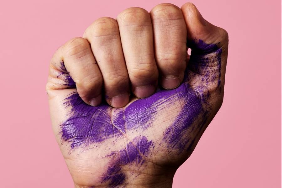 Mulher com a mão fechada pintada de lilás como símbolo de luta na campanha Agosto Lilás.