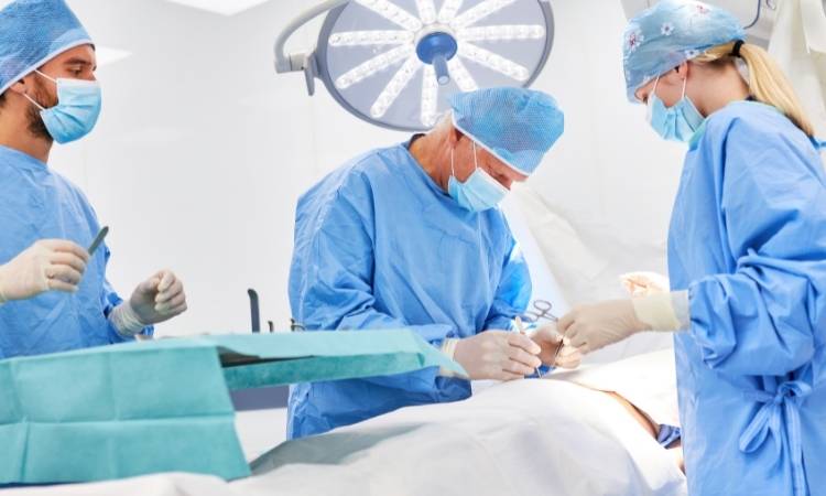 Equipe médica de jalecos azuis realizando cirurgia de apendicite