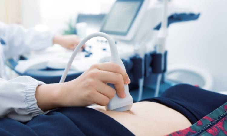 Exame de ultrassom para diagnóstico de apendicite. Médico realizando exame de ultrassom na barriga de uma mulher