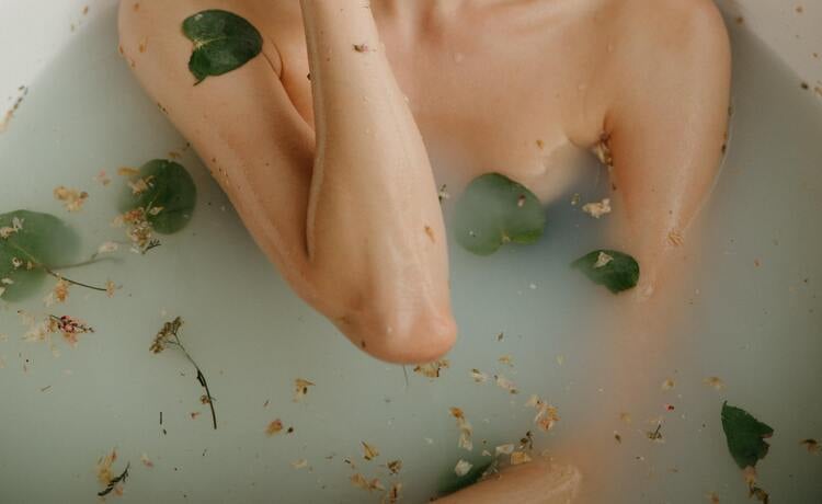 busto e braços de uma mulher em uma banheira com banho de ervas