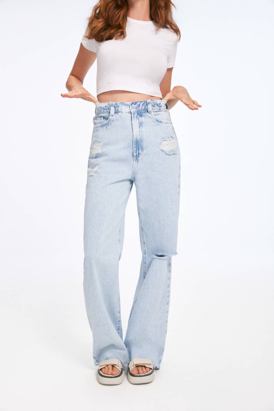 Imagem de mulher mostrando calça jeans wide leg, compondo com um cropped branco simples