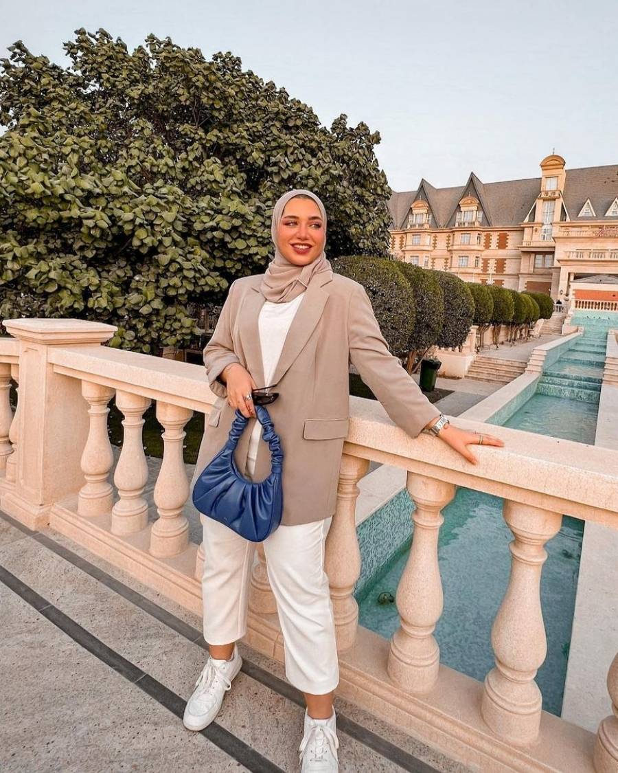mulher com hijab e blazer cáqui, blusa, calça e tênis brancos