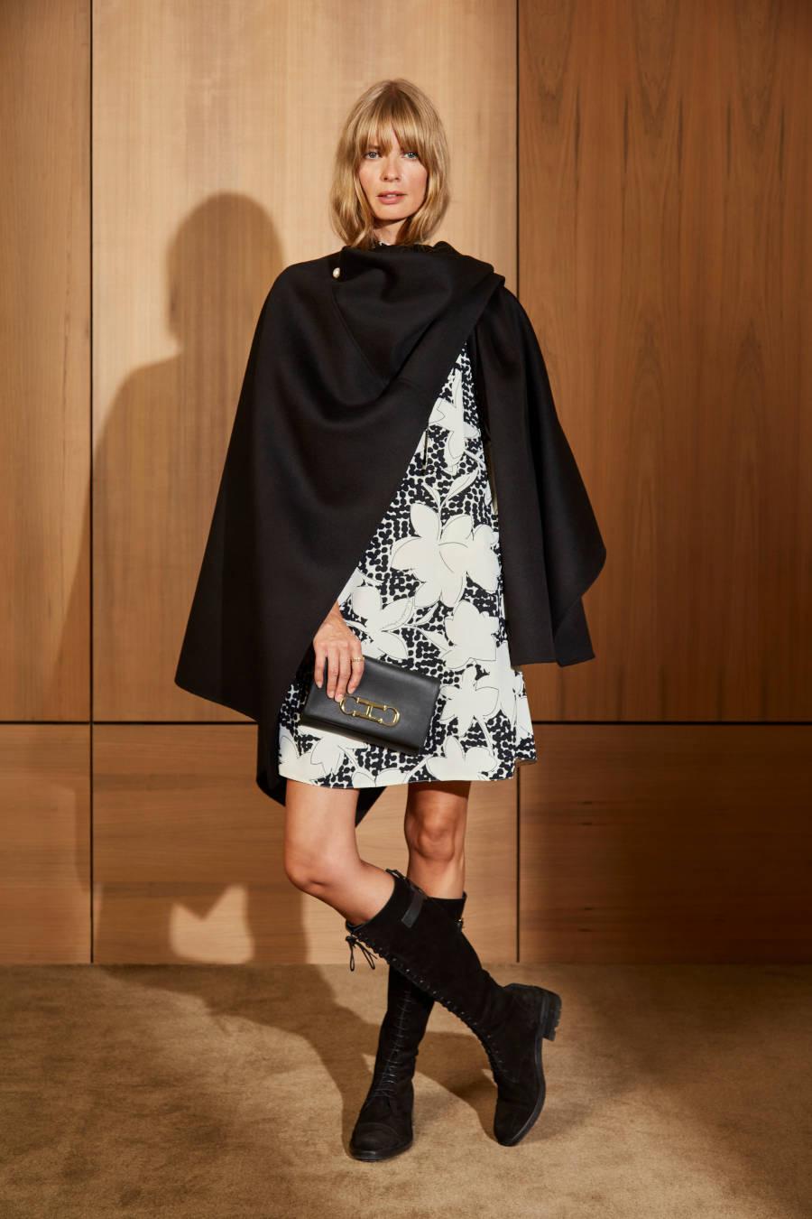 Foto de modelo usando vestido estampado com parka em cima e bota de cano alto e bolsa Carolina Herrera