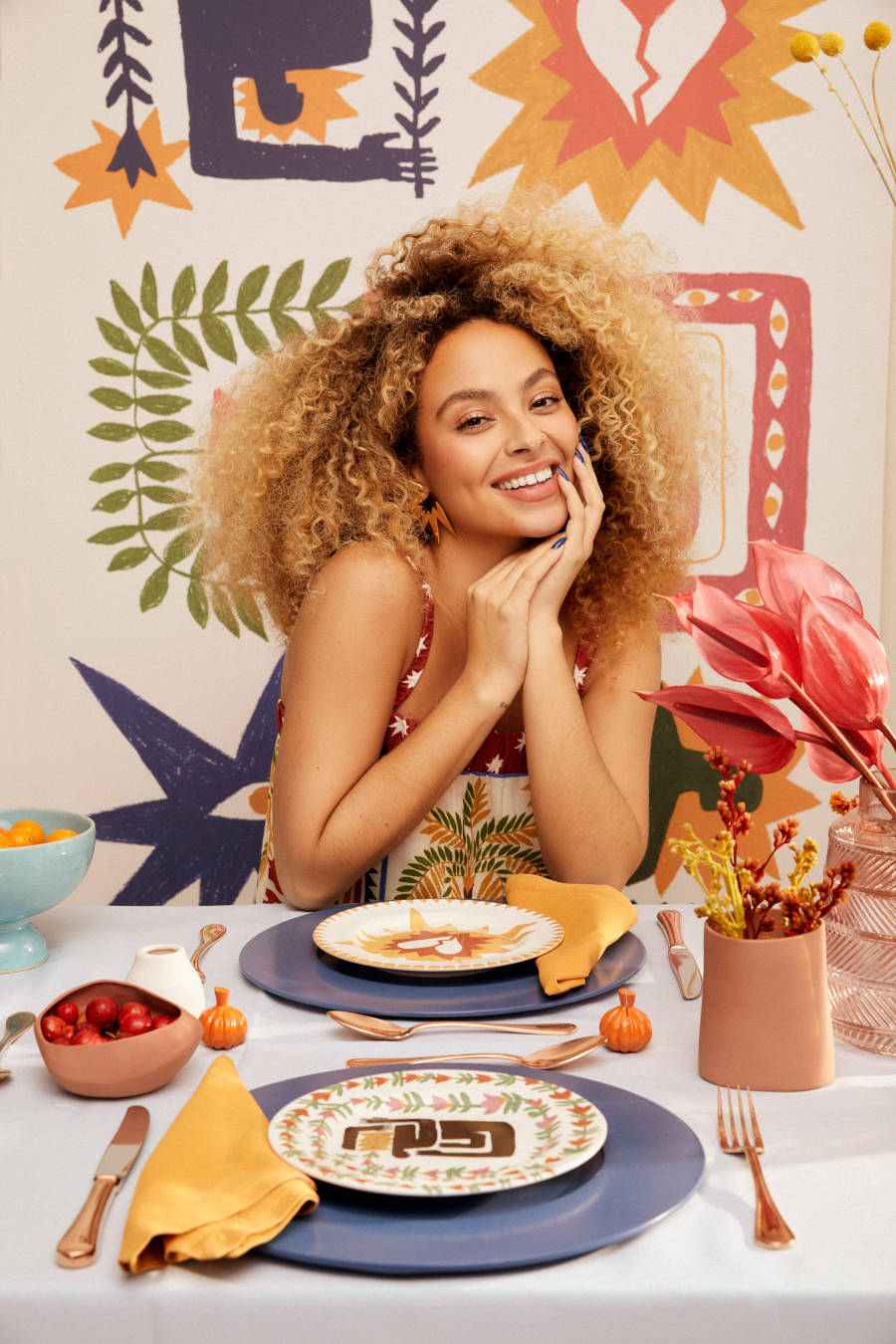 Foto de modelo sentada à mesa com pratos da nova coleção da Riachuelo