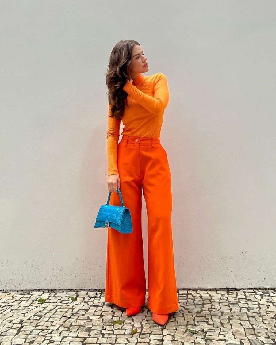 Lele Burnier usando look todo laranja com bolsa azul vibrante