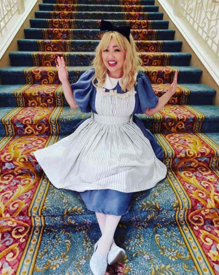 Foto de mulher sentada em uma escadaria com a fantasia de Alice no País das Maravilhas