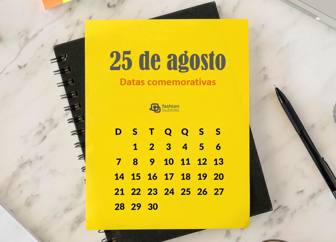 Foto de calendário amarelo sobre caderno preto com a data 25 de agosto. Itens estão sobre superfície.