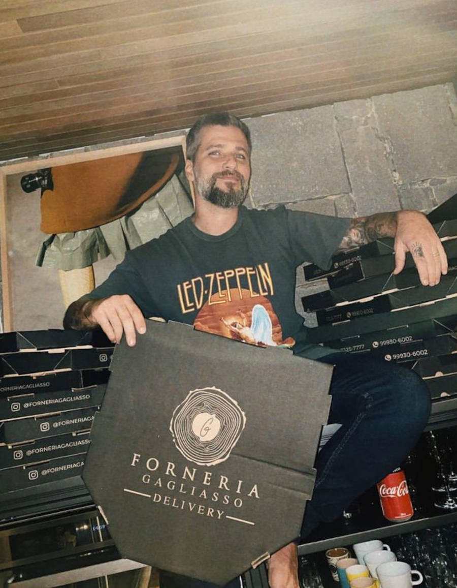 Imagem de Bruno Gagliasso em volta de caixa de pizzas e segurando a frente da caixa, onde está escrito "Forneria Gagliasso"