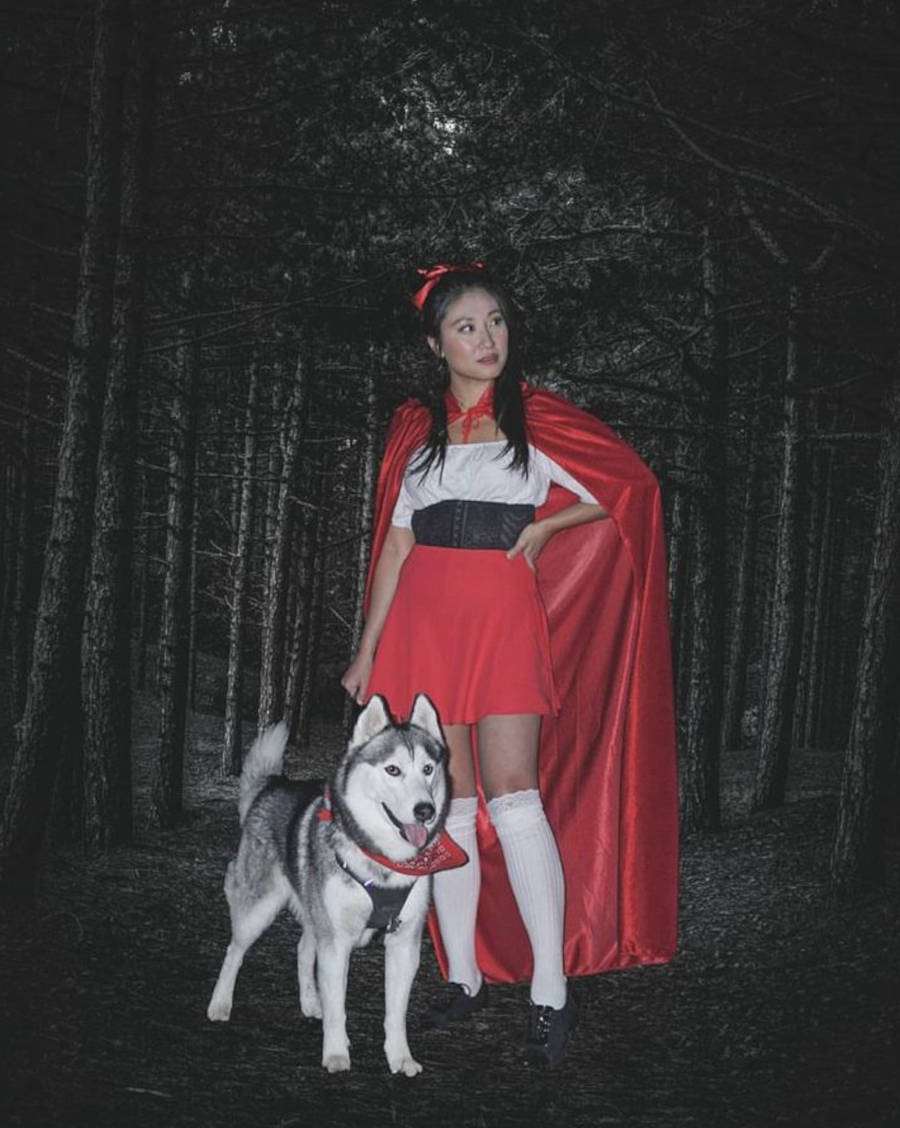 Foto de mulher fantasiada para o Halloween de Chapeuzinho Vermelho com o seu cachorro Husky Siberiano