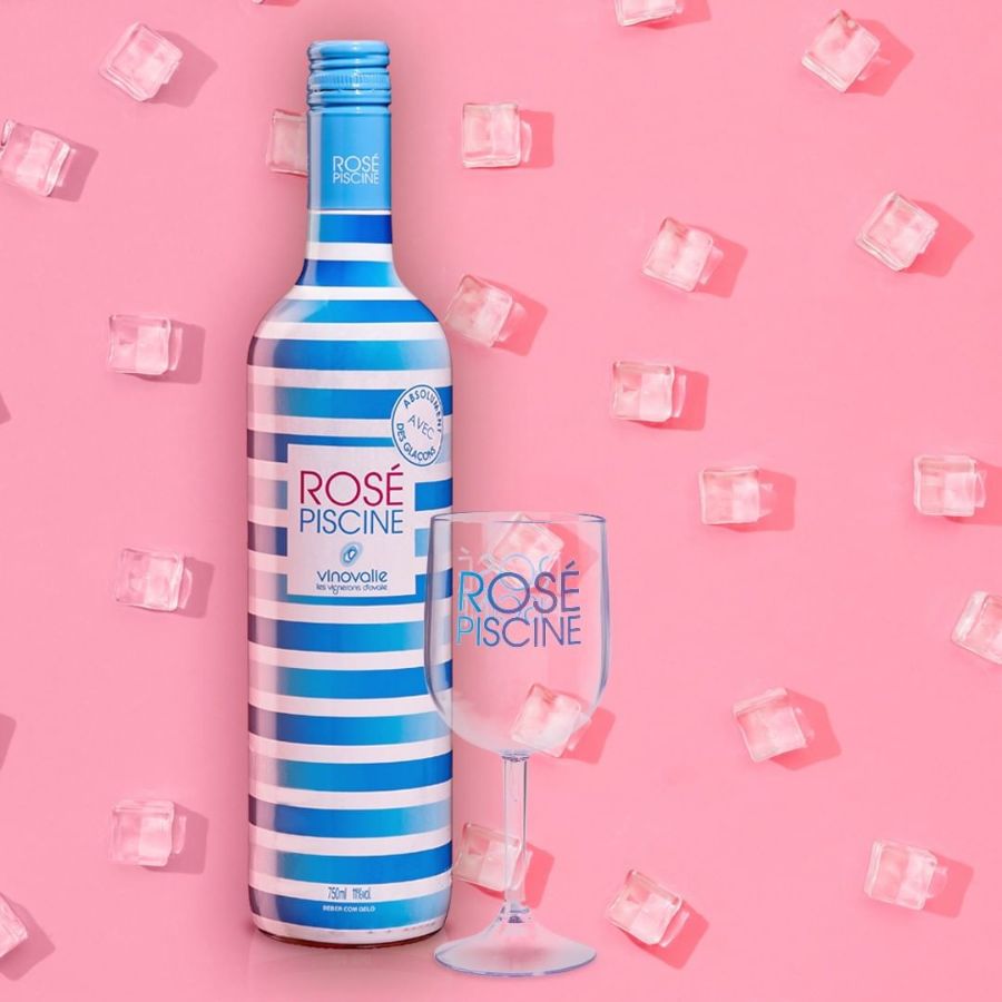 foto do vinho Rosé Piscine com taça de vidro em fundo rosa com pedras de gelo
