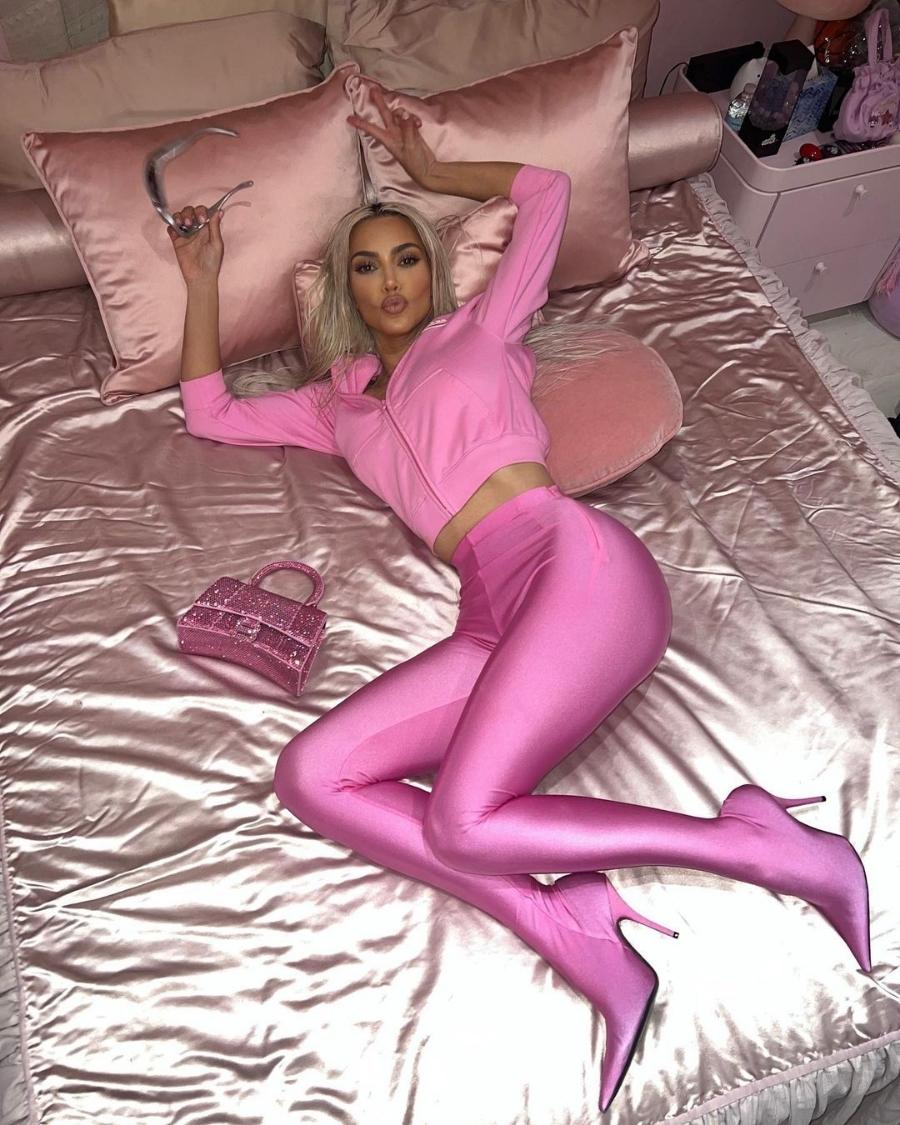 Foto de Kim Kardashian usando look Barbiecore deitada na cama