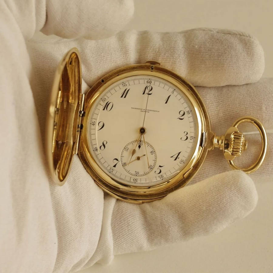 Foto de um relógio de época de Vacheron Constantin em Chromo, posto em uma mão com luvas brancas