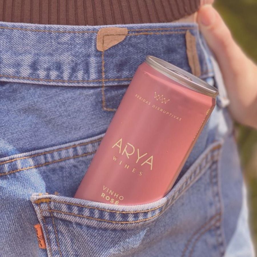 bolso de calça jeans com lata de vinho rosé da marca Arya Wines, mostrando praticidade desse vinho para a primavera