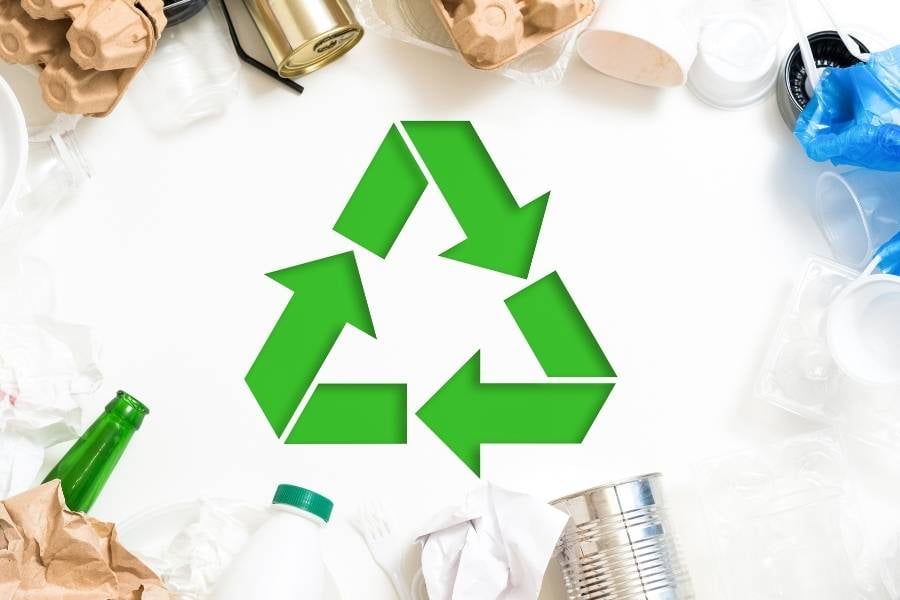 Foto com vários tipos de lixo e símbolo de reciclagem ao meio como prática do ESG.