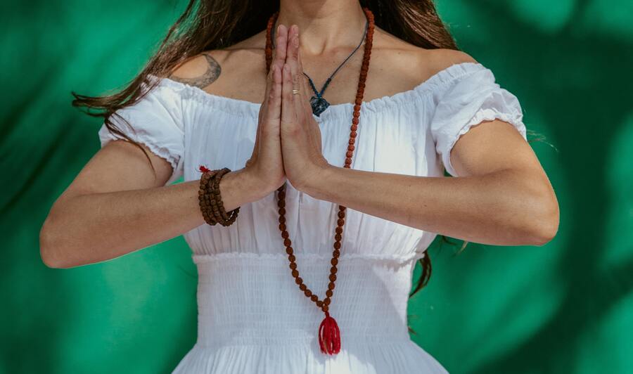 mulher com japamala e mãos em formato de oração para realizar Ho'oponopono