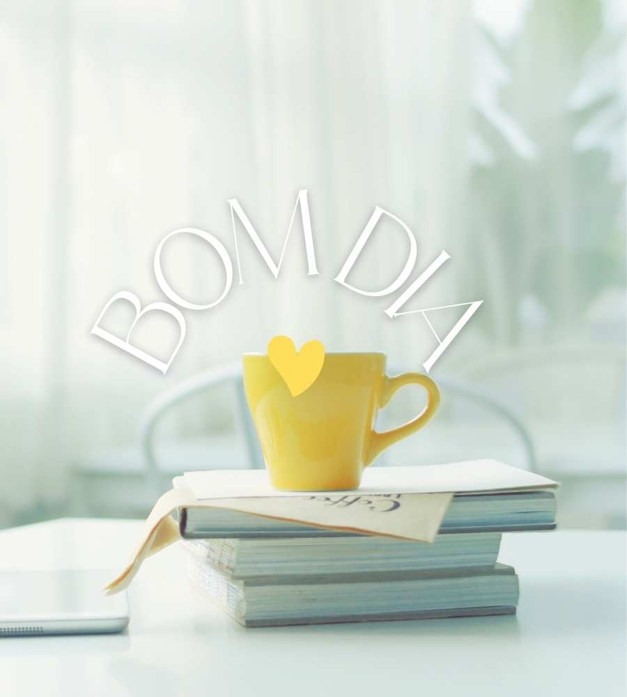 "Bom dia" escrito em foto de livros, caneca e tablets sobre uma mesa com cadeiras em uma casa, com vista para janela com cortinas.