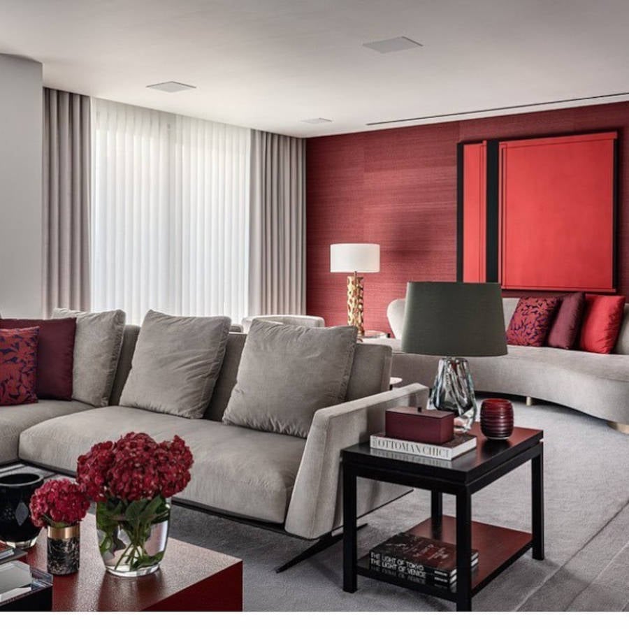Sala de estar com dois sofás cinzas e detalhes vermelhos.