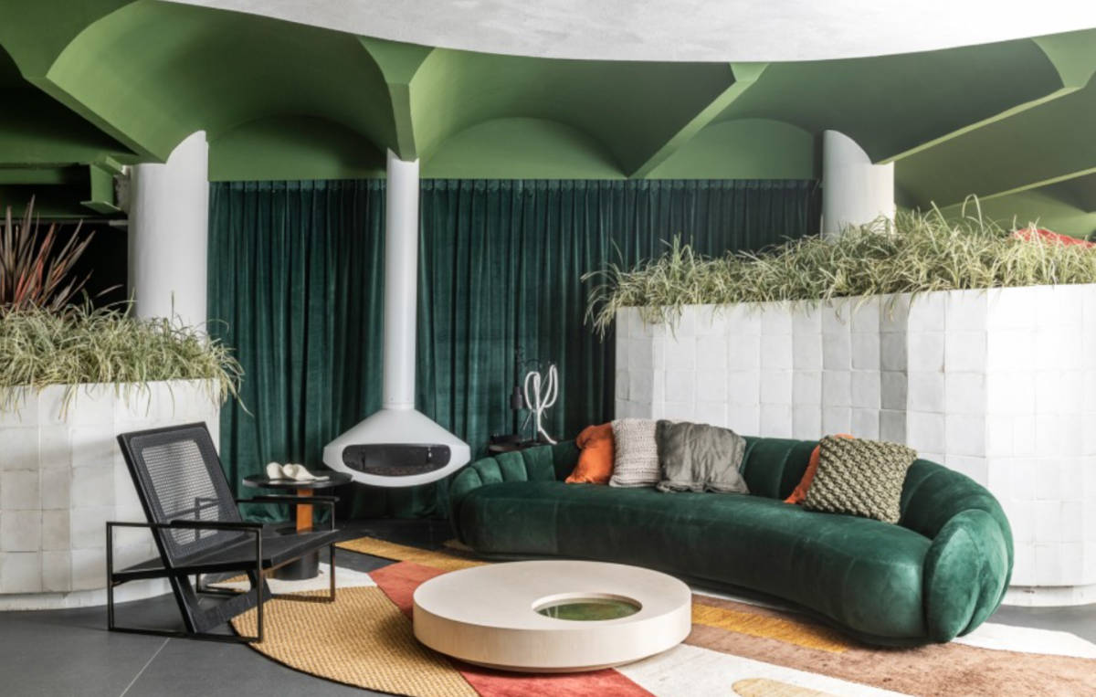 Decoração da CASACOR SP com sofá verde e lareira.