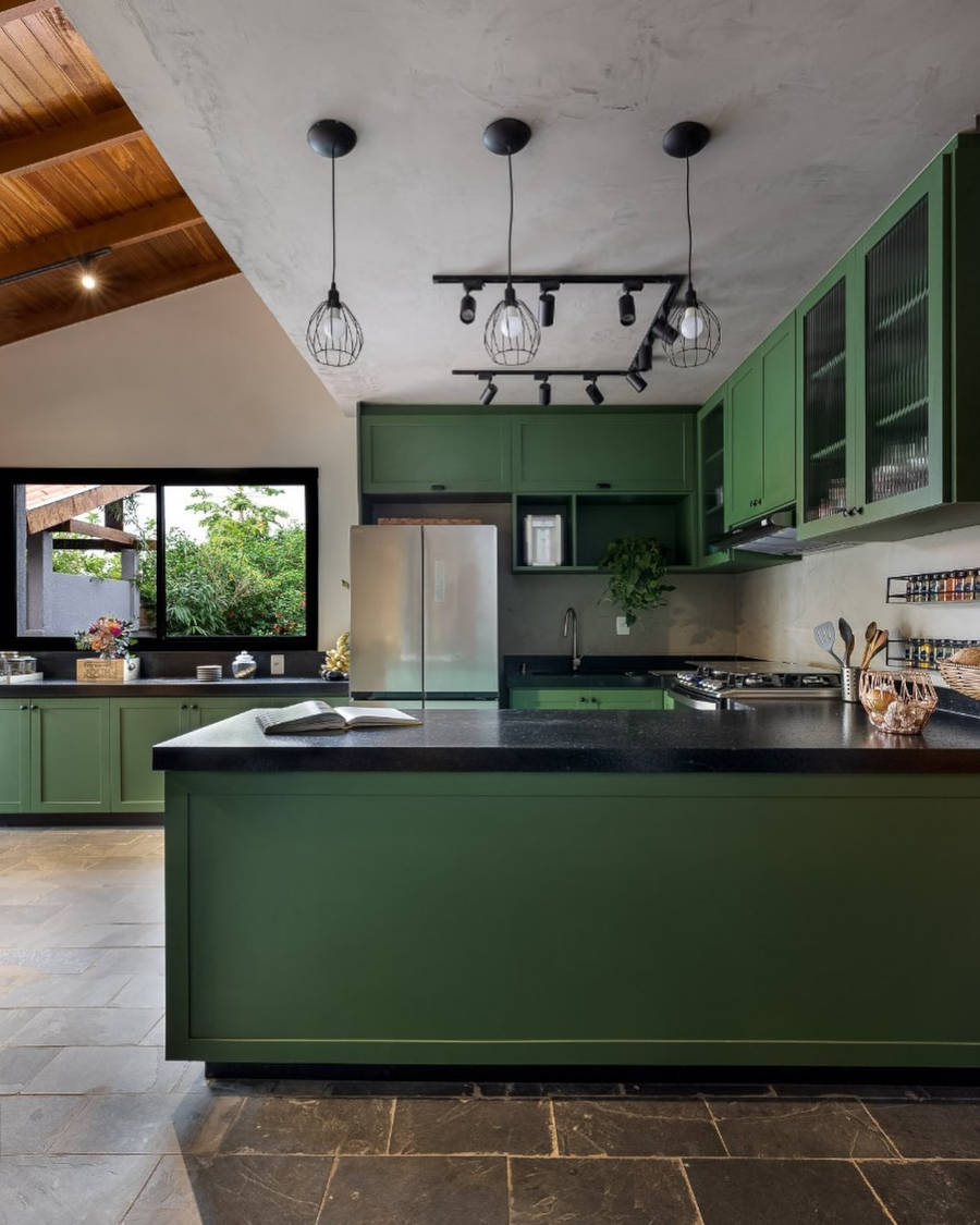 Cozinha americana com armários verdes e pretos.