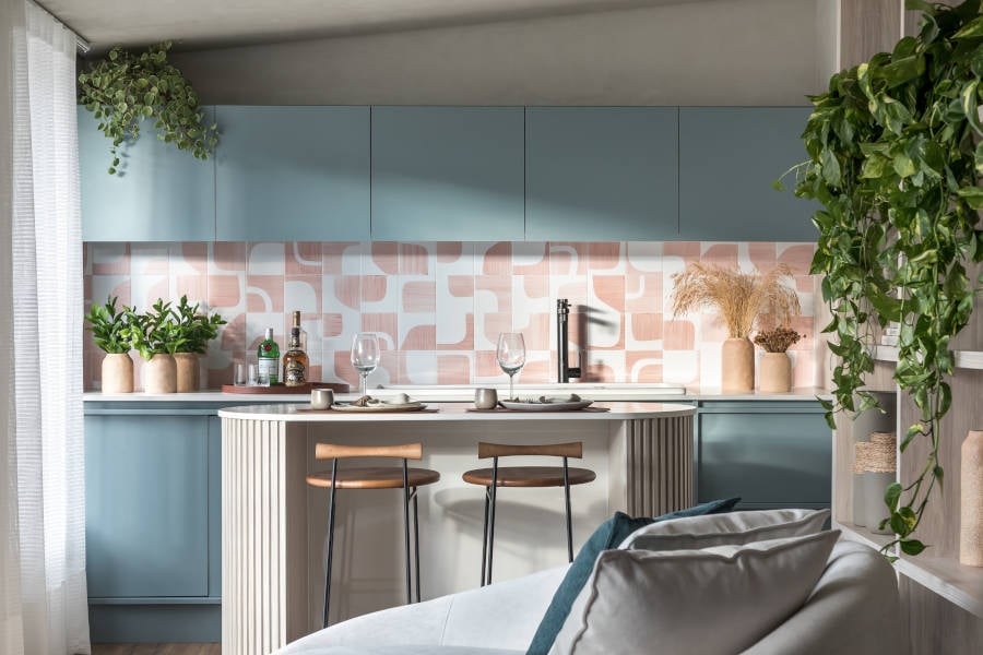 Cozinha americana com armários azuis e parede com azulejo branco e rosa.
