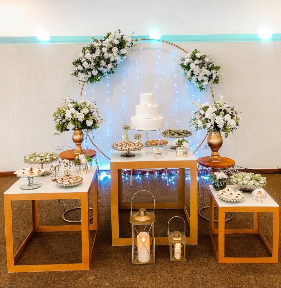 Decoração de casamento simples com fundo branco e mesas de madeira.