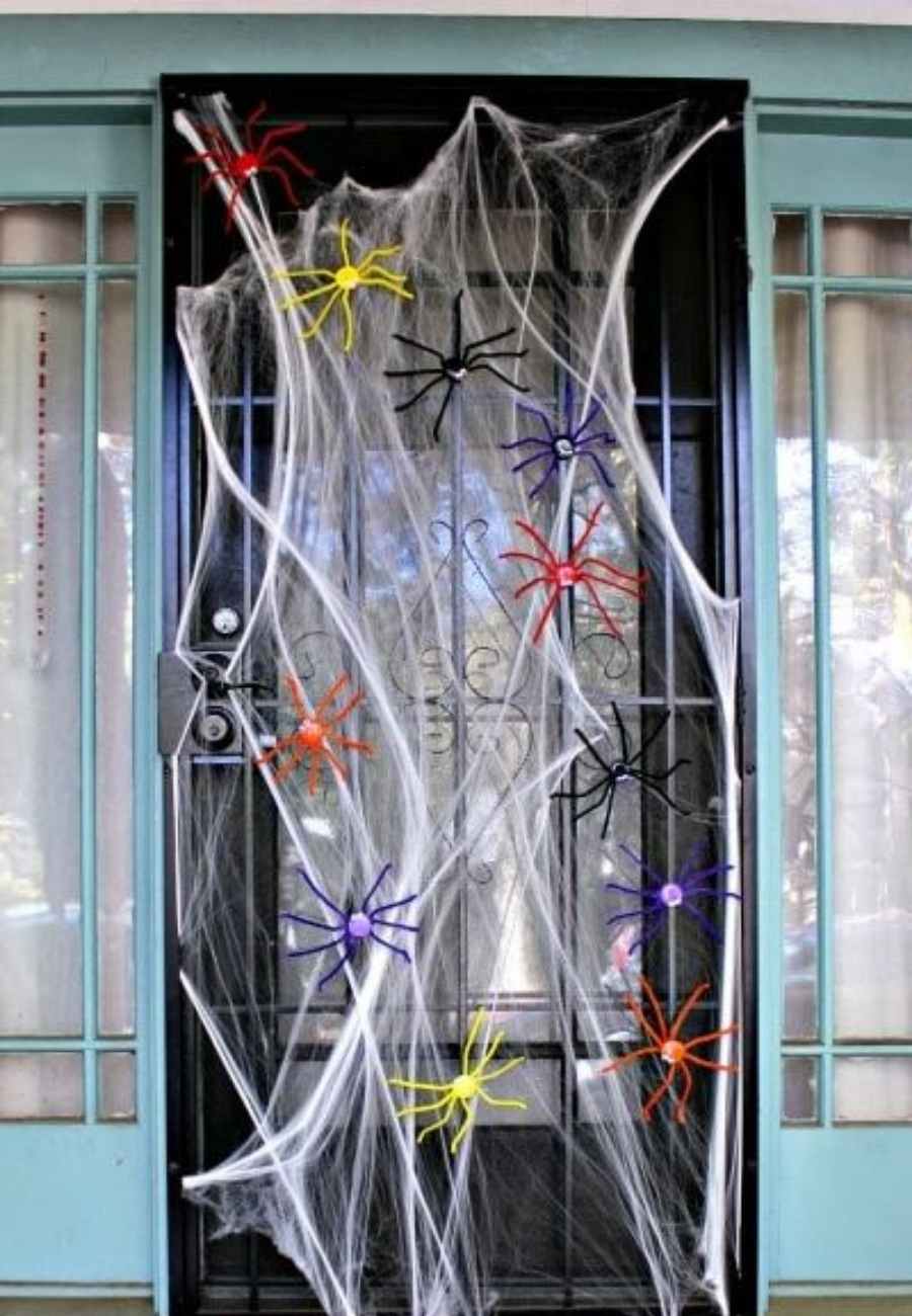 Porta de Halloween com teia de aranha e aranhas coloridas de plástico.