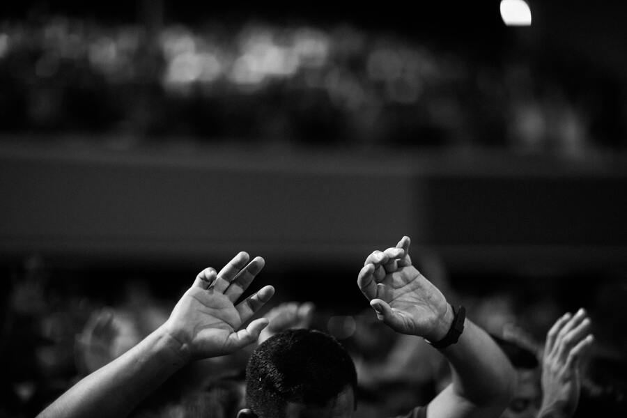foto em preto e branco de homem com mãos para cima em forma de prece