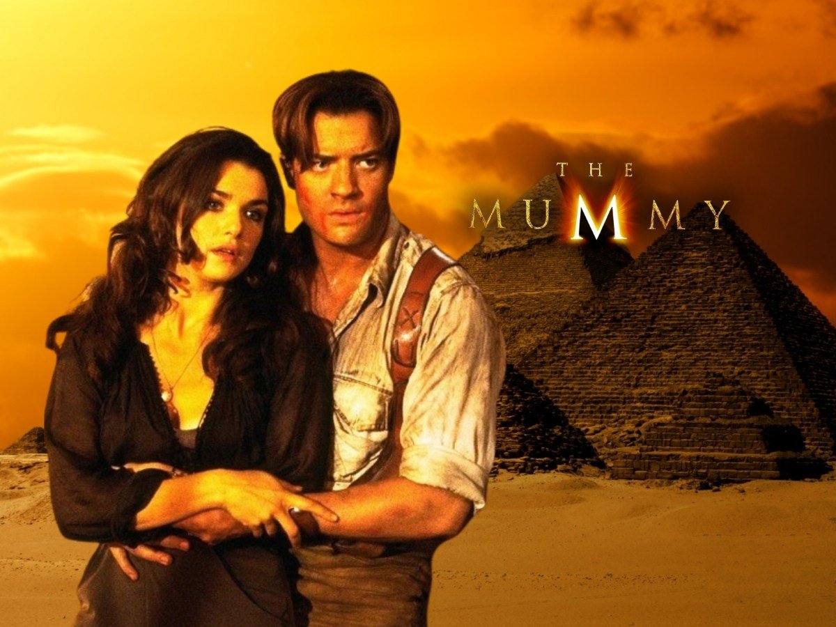 Foto dos dois atores principais do filme "A Múmia" em cena. Fundo foto das pirâmides do Egito.