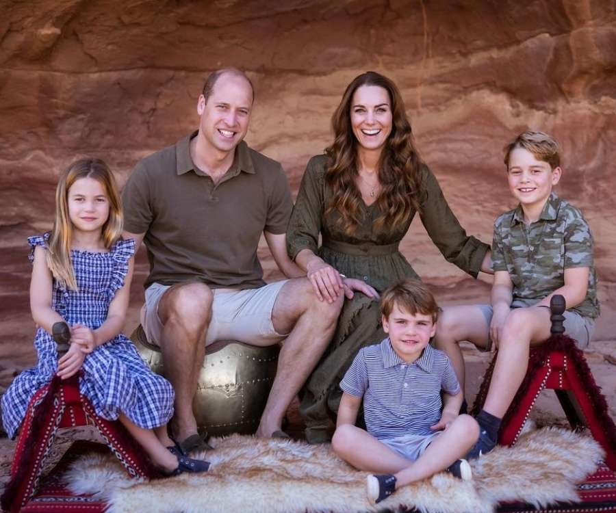A família do príncipe William unida. Estão sentados em objetos de cenário fotográfico e, ao fundo, uma textura que aparenta de terra, montanha.