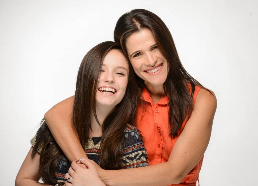 Fotos das atrizes Larissa Manoela e ingrid Guimarães abraçadas. Elas estão sorridentes e em fundo branco.