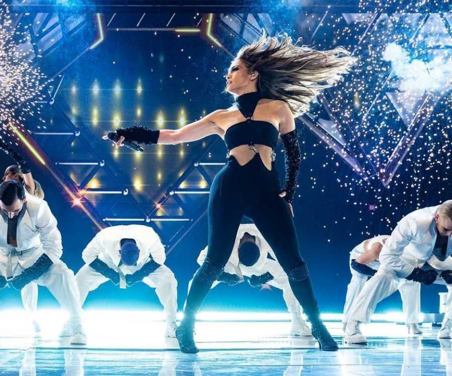 Jennifer Lopez apresentando show em palco e ao lado de dançarinos.