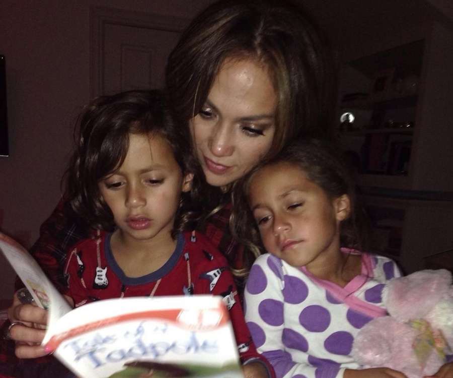 Foto antiga da cantora lendo livro para seus filhos ainda crianças.