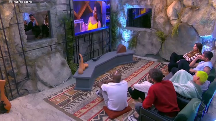 Exilados assistem pela TV da caverna a briga entre Solange e Jaciara.