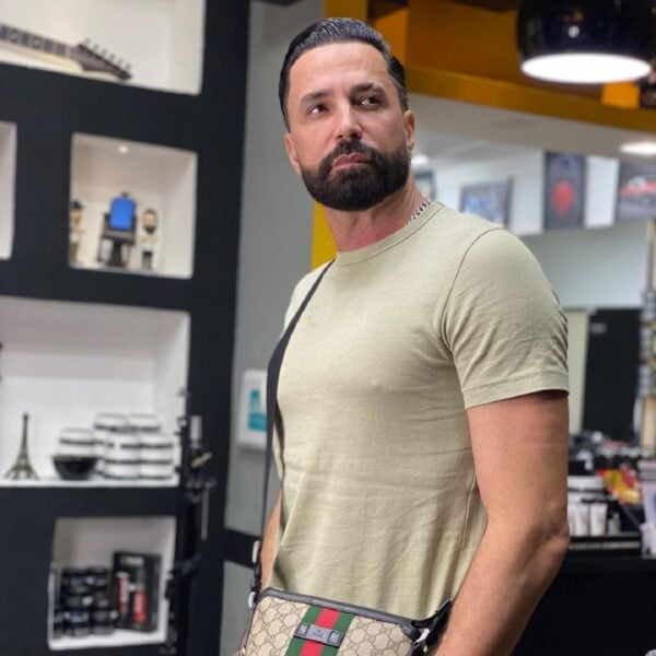 Foto de Latino com camiseta básica cor bege e uma bolsa tiracolo