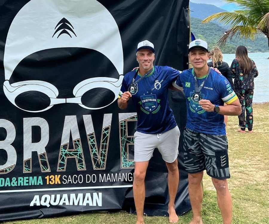 Foto de João Paulo Diniz e Juraci Moreira em pé de frente a painel da Brave Nada&Rema no Desafio Aquaman.