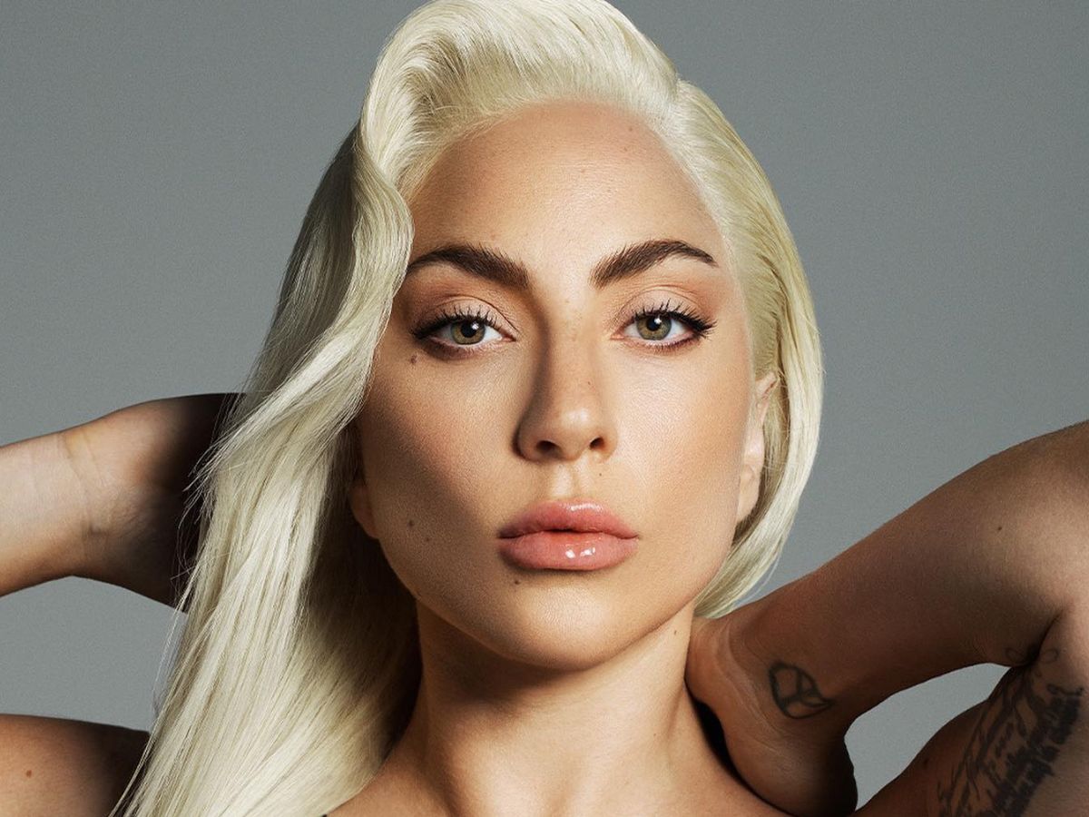 Foto do rosto de Lady Gaga. Cantora está com as duas mãos na nuca.