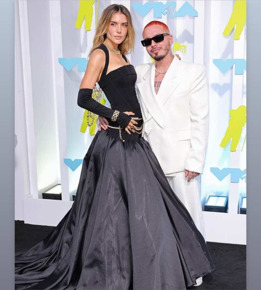 Foto de Valentina Ferrer e J Balvin no VMA 2022. Eles estão abraçados, ela veste vestido preto longo, e ele um terno moderno branco.