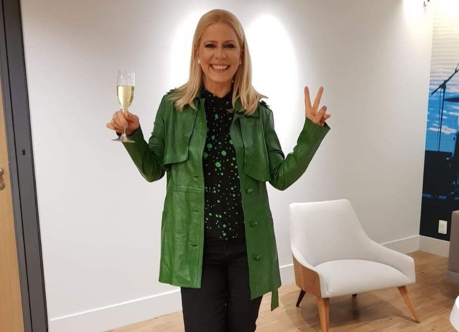 Paula do Kid Abelha com sobretudo verde e taça de champanhe