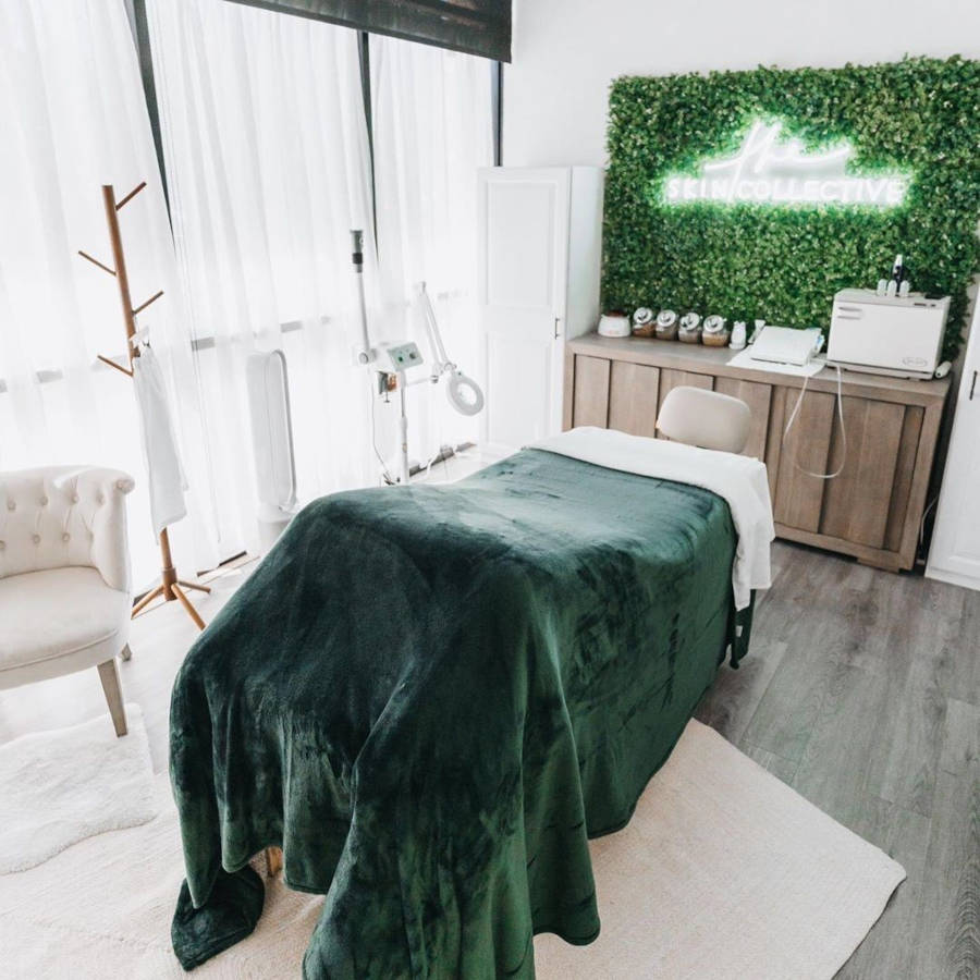 Quarto de massagem com parede verde e letreiro neon.