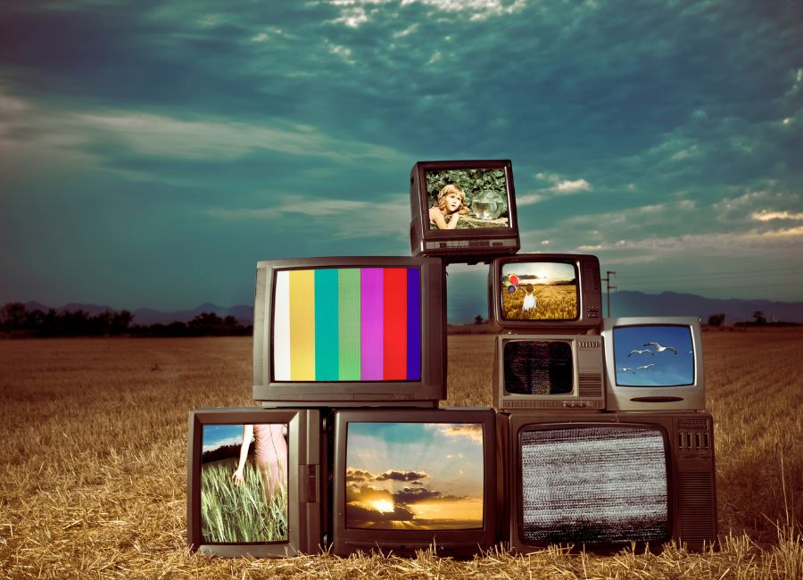Imagem de várias televisões mostrando programas diferentes e empilhadas