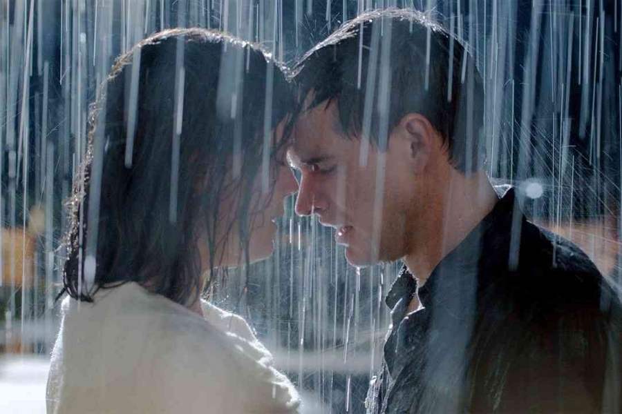 Foto de Ava (Erin Bethea) e Ben Morton (Jonathan Wood) prestes a se beijar, eles estão em área externa tomando chuva.