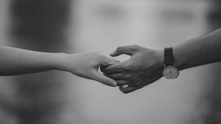 foto em preto e branco com uma mão masculina segurando uma feminina