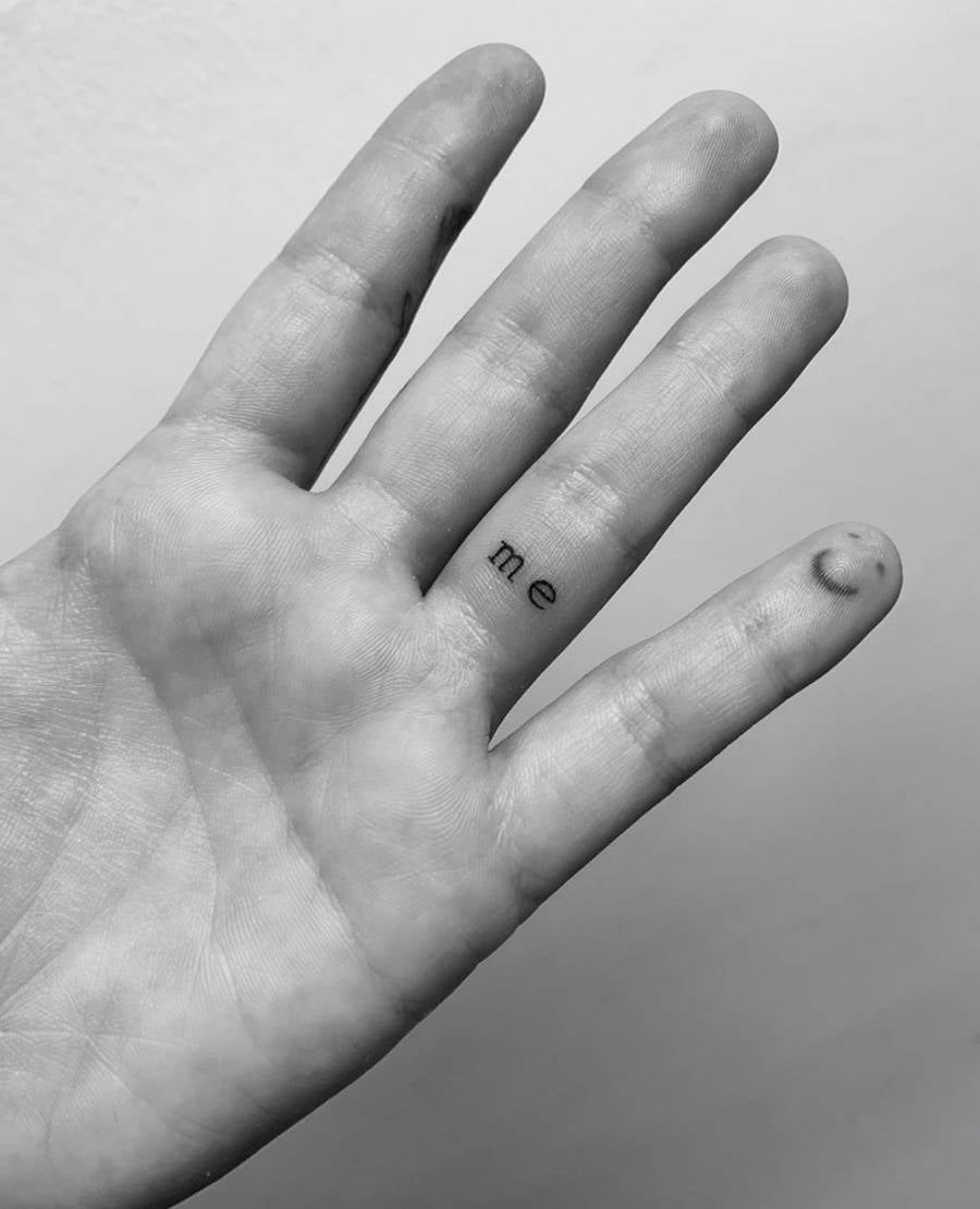 Foto da mão de Demi Lovato com duas tatuagens uma carinha sorrindo no mindinho e a palavra "me" no dedo anelar